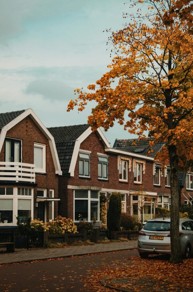 pexels-photo-3100371-3100371 Picturesque suburban street with row houses and autumn foliage under a cloudy sky.